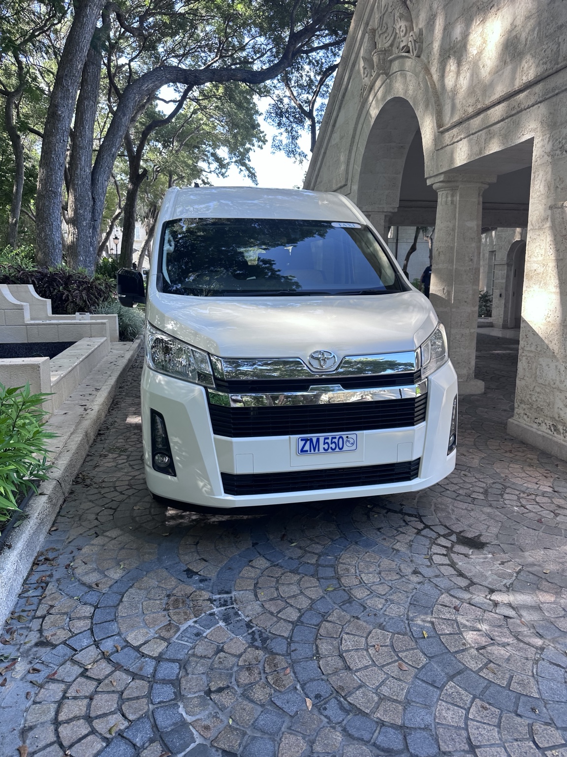 Our white Toyota Hiace ready for pickup on a shaded Barbados driveway